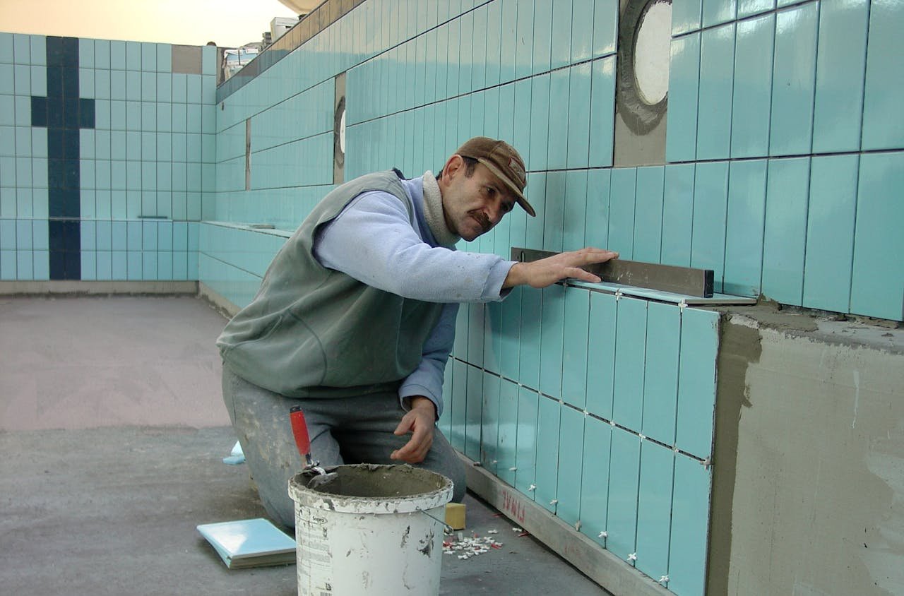 Tiler expertly aligns ceramic tiles on a swimming pool wall. Indoor construction setting in Wrocław.